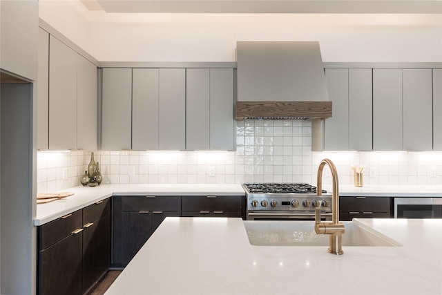 kitchen with light countertops, high end stainless steel range, custom range hood, and modern cabinets