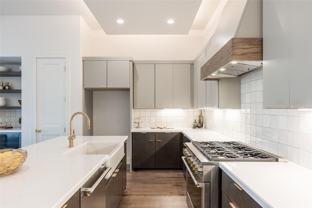 kitchen featuring a sink, dark wood finished floors, stainless steel appliances, light countertops, and custom exhaust hood