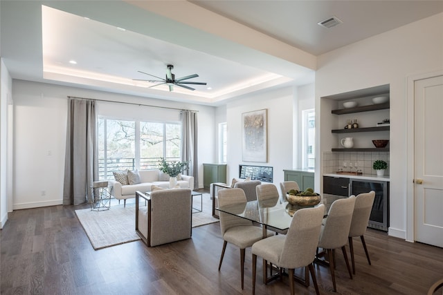 dining area featuring a raised ceiling, wine cooler, dark wood-style floors, and visible vents