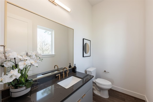 bathroom featuring vanity, toilet, wood finished floors, and baseboards