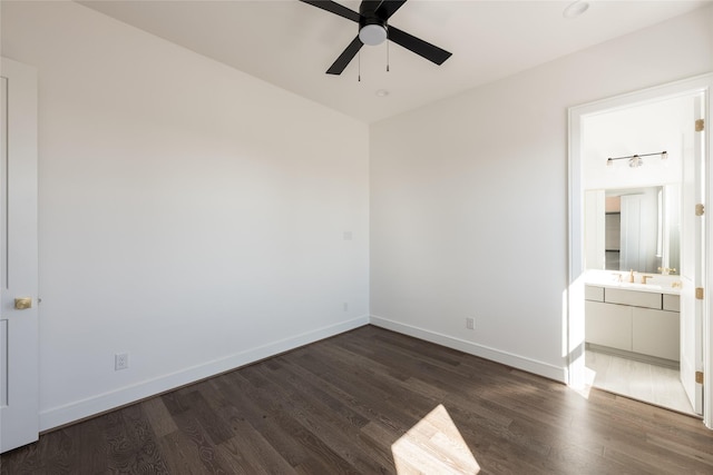 unfurnished bedroom with a sink, baseboards, ensuite bath, and dark wood-style floors