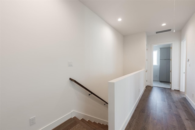 hall with an upstairs landing, visible vents, baseboards, and dark wood-style floors