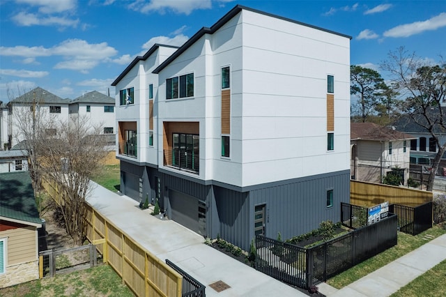 view of property exterior with a garage, a residential view, and fence