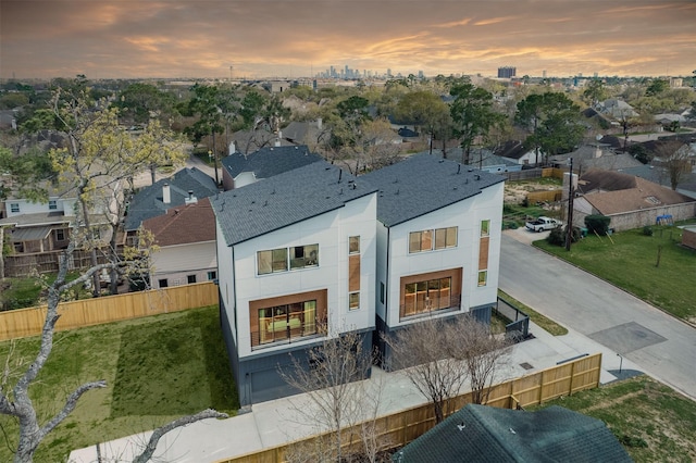 rear view of property featuring stucco siding, a shingled roof, and fence