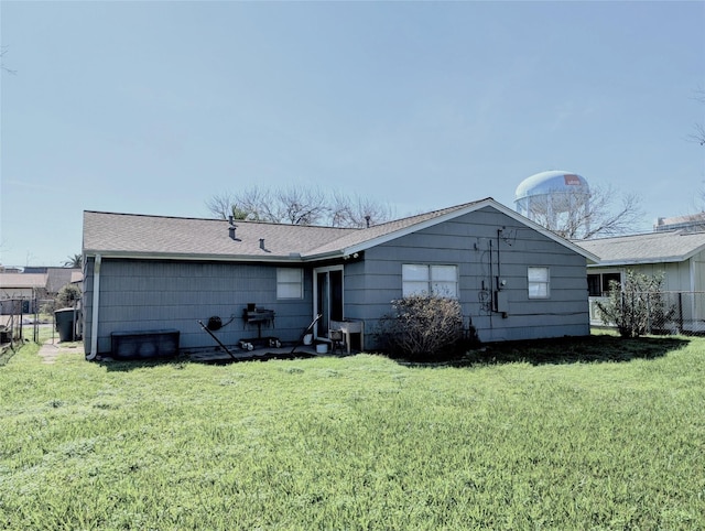 back of house featuring a lawn and fence