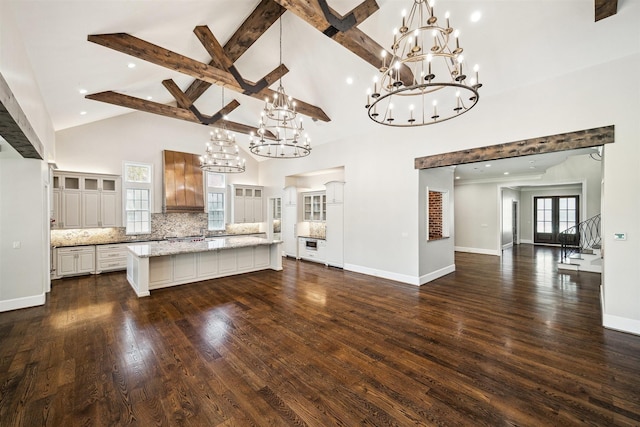 kitchen with decorative backsplash, a large island, glass insert cabinets, and a chandelier