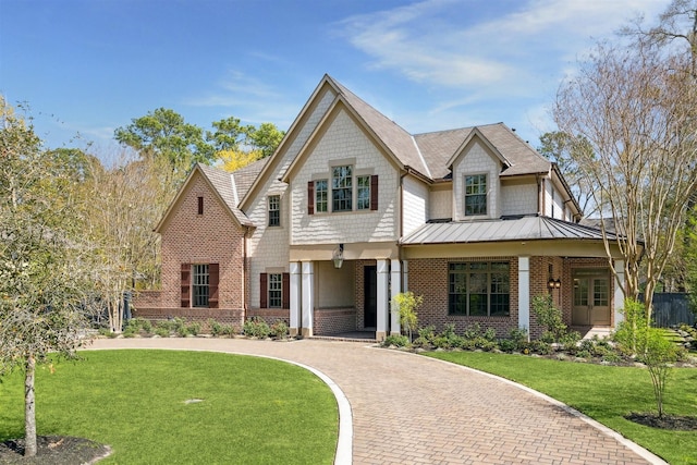 view of front of home with brick siding, a standing seam roof, metal roof, and a front lawn