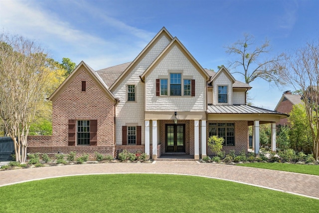 view of front of home with a front lawn, french doors, and brick siding