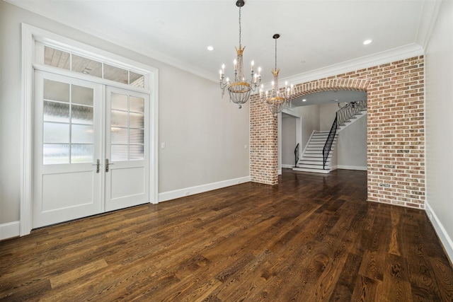 unfurnished dining area featuring stairway, wood finished floors, brick wall, and a chandelier