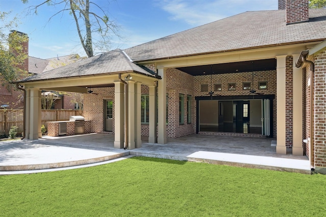 back of house featuring a patio area, brick siding, an outdoor kitchen, and fence