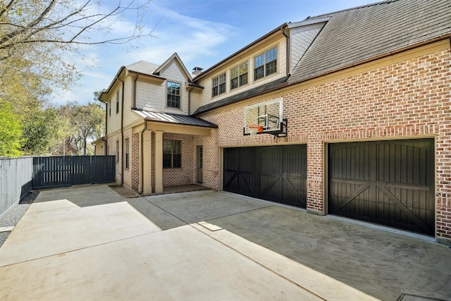 rear view of house with concrete driveway, an attached garage, fence, and brick siding