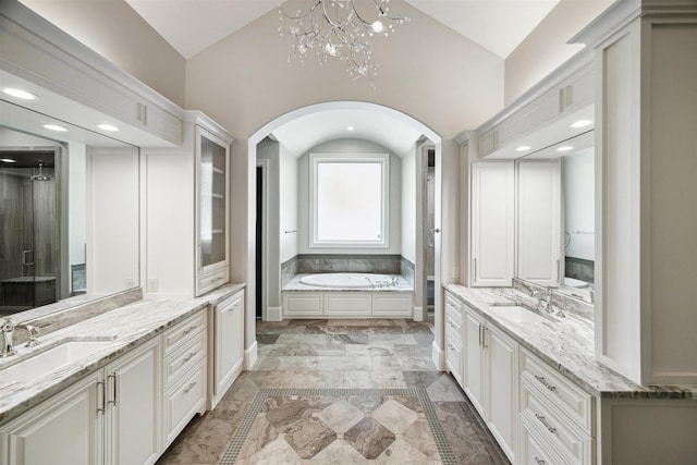 bathroom with a garden tub, two vanities, recessed lighting, and a sink