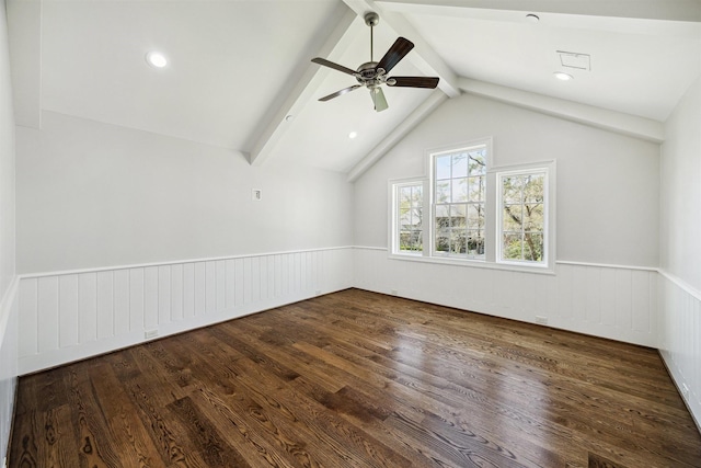 empty room featuring a ceiling fan, lofted ceiling with beams, wood finished floors, and wainscoting