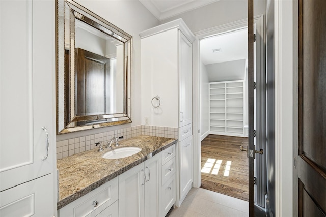 bathroom with decorative backsplash, wood finished floors, ornamental molding, and vanity