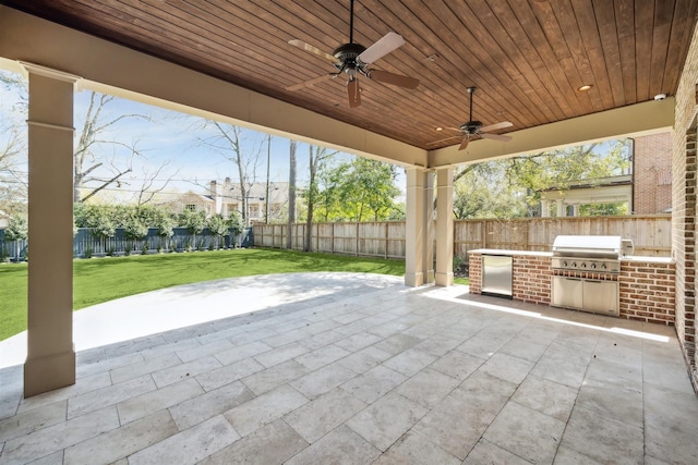 view of patio with ceiling fan, area for grilling, an outdoor kitchen, and fence