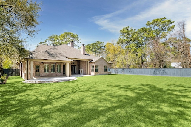 back of house with a lawn, a patio, a fenced backyard, brick siding, and ceiling fan