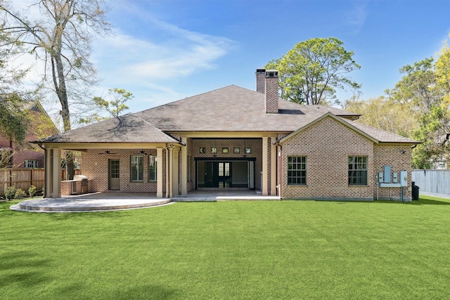 back of property with a ceiling fan, a patio area, a yard, and fence