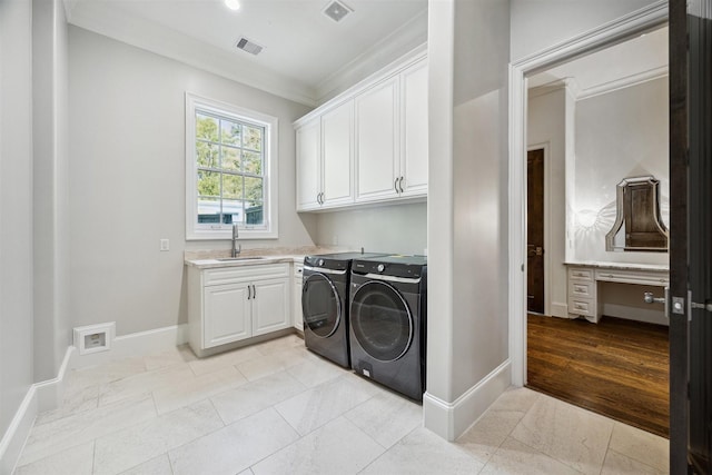 laundry area featuring visible vents, a sink, cabinet space, baseboards, and washing machine and clothes dryer