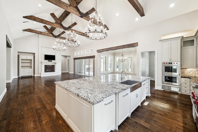 kitchen with dark wood-type flooring, stainless steel double oven, a notable chandelier, a warming drawer, and a sink