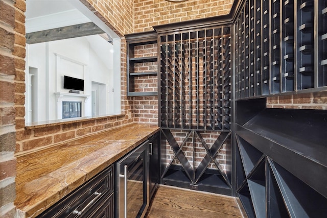 wine cellar featuring wine cooler and brick wall