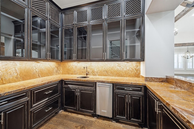 kitchen with dark wood-style floors, an inviting chandelier, a sink, decorative backsplash, and glass insert cabinets