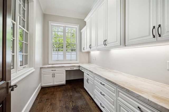 home office with built in desk, ornamental molding, baseboards, and dark wood-style flooring