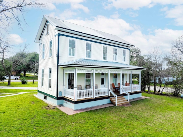 view of front of property with metal roof, covered porch, and a front lawn