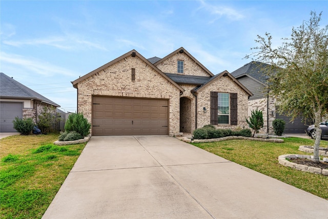 french country style house featuring a front lawn, concrete driveway, brick siding, and an attached garage