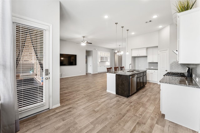 kitchen featuring visible vents, dishwasher, ceiling fan with notable chandelier, light wood-style flooring, and a sink