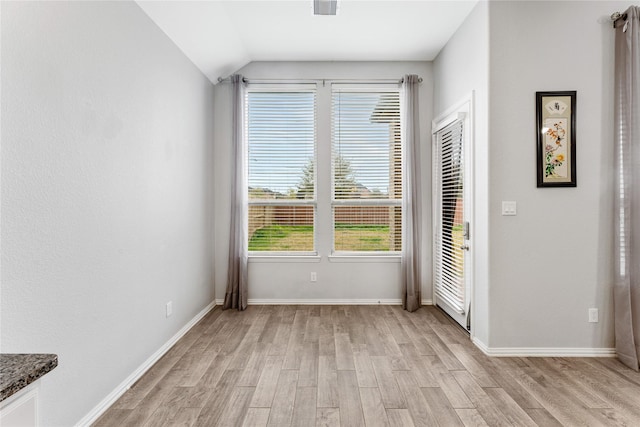 unfurnished room with visible vents, baseboards, light wood-style flooring, and vaulted ceiling