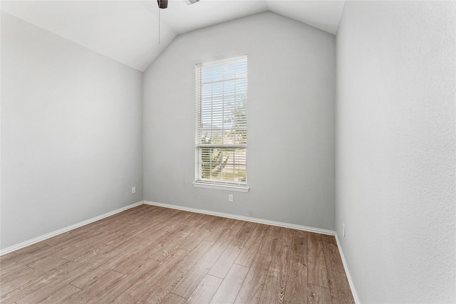 empty room with a ceiling fan, lofted ceiling, light wood-style floors, and baseboards