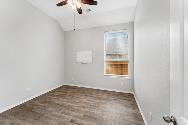 empty room featuring visible vents, a ceiling fan, wood finished floors, baseboards, and vaulted ceiling