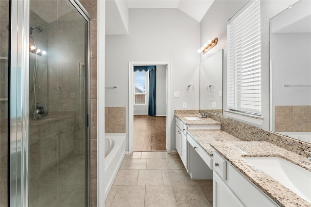 bathroom featuring a shower stall, lofted ceiling, double vanity, a bath, and a sink