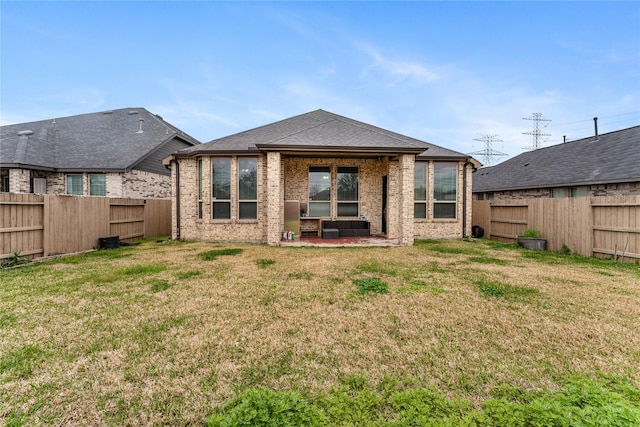 rear view of house featuring brick siding, a fenced backyard, and a lawn