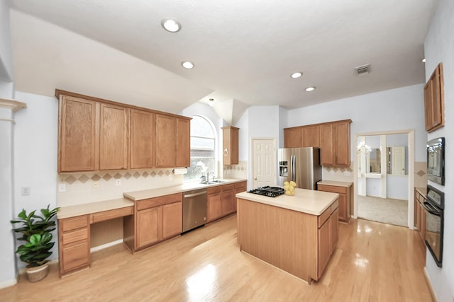 kitchen featuring tasteful backsplash, visible vents, a center island, black appliances, and a sink