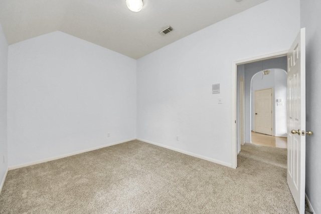 carpeted empty room featuring lofted ceiling, baseboards, and visible vents