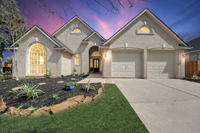 view of front facade with brick siding, concrete driveway, a garage, and fence