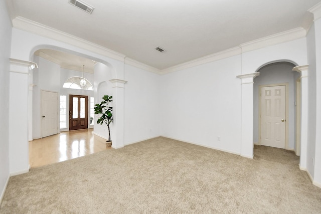 spare room featuring visible vents, ornamental molding, carpet floors, arched walkways, and ornate columns