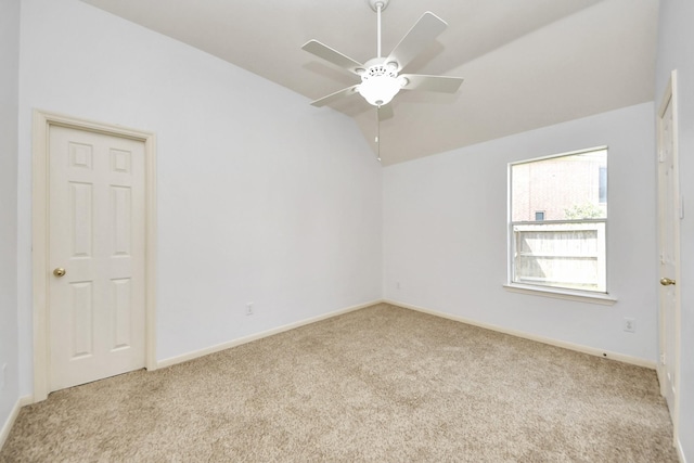 empty room with carpet flooring, baseboards, ceiling fan, and vaulted ceiling