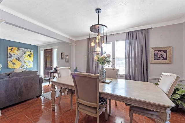 dining space featuring a textured ceiling, ornamental molding, and ornate columns