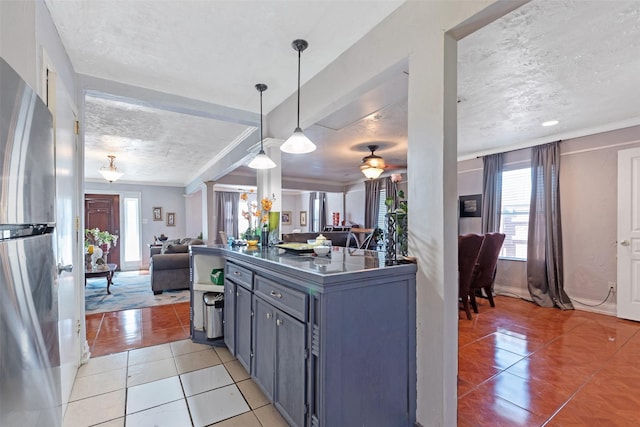 kitchen with decorative light fixtures, a textured ceiling, dark countertops, open floor plan, and light tile patterned floors