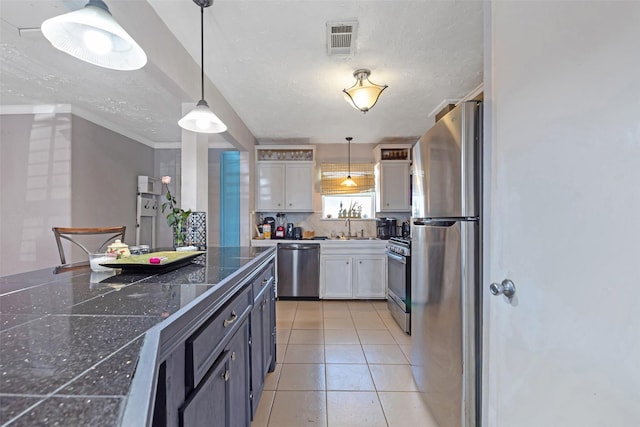 kitchen featuring tile countertops, light tile patterned floors, visible vents, white cabinets, and appliances with stainless steel finishes