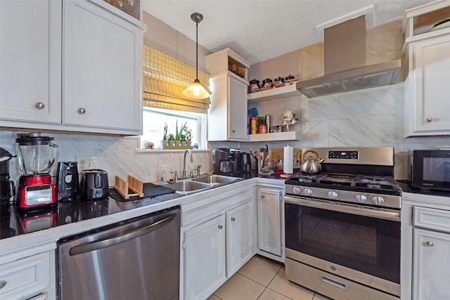 kitchen with tasteful backsplash, wall chimney range hood, appliances with stainless steel finishes, white cabinetry, and a sink