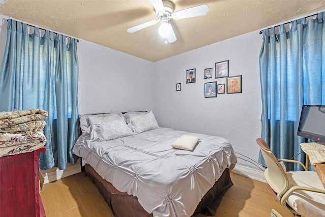 bedroom featuring a textured ceiling, baseboards, ceiling fan, and wood finished floors