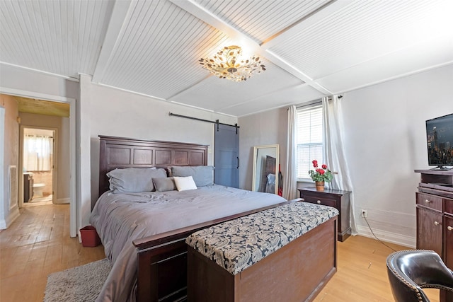 bedroom with light wood finished floors, beamed ceiling, a barn door, and baseboards