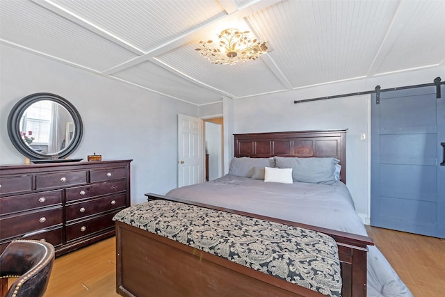 bedroom with light wood-type flooring and a barn door