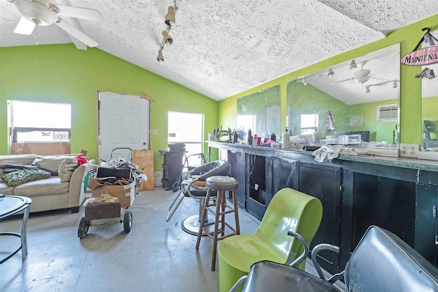 misc room with a textured ceiling, concrete floors, a ceiling fan, and vaulted ceiling