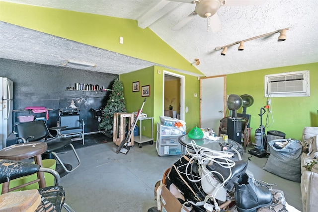 interior space with an AC wall unit, a ceiling fan, and freestanding refrigerator