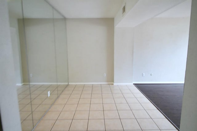 empty room featuring visible vents, baseboards, and tile patterned flooring