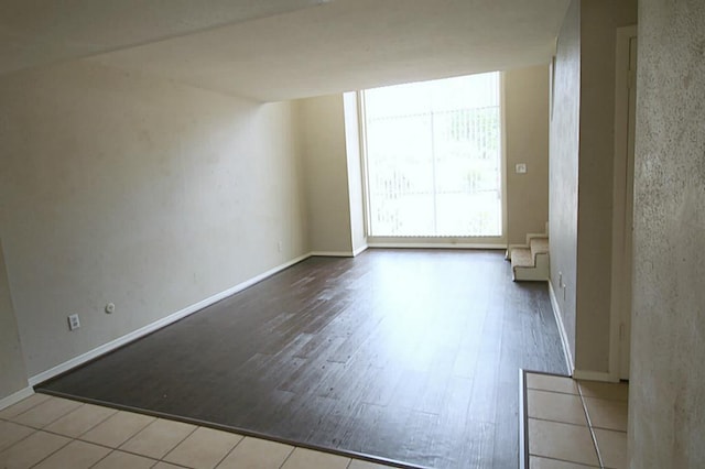 spare room with baseboards and wood finished floors